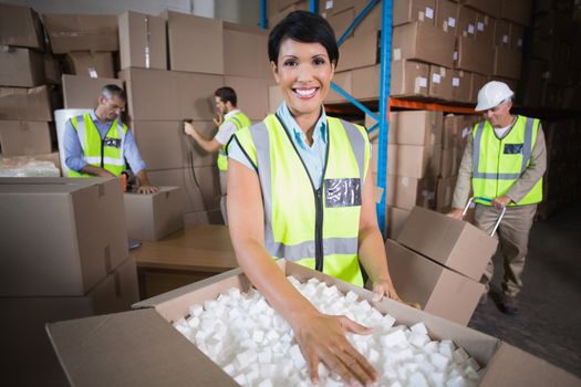 Warehouse workers in yellow vests preparing a shipment in a large warehouse