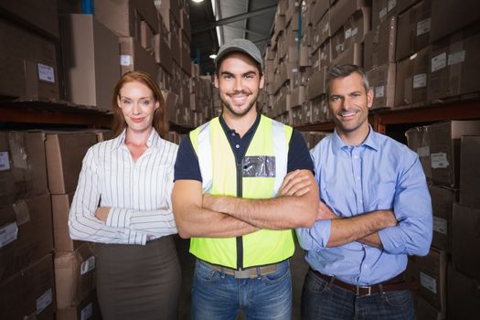 Warehouse team smiling at camera showing thumbs up in a large warehouse