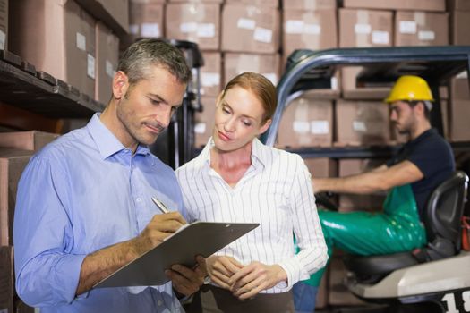 Warehouse team working together with clipboard in a large warehouse