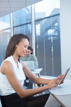 Female executive using digital tablet at desk in office