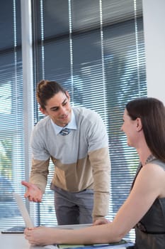 Business executives discussing over laptop at desk in office