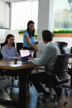 Smiling executives shaking hands in the office