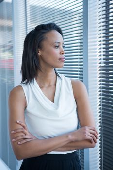 Beautiful female executives looking through window in office