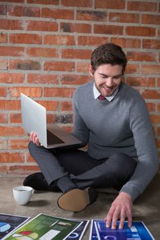 Executive using laptop while looking at document in office