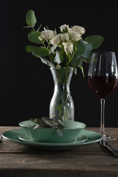 Setting a table for a dinner party with wine glass and flower vase on table