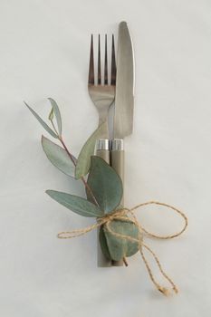 Close-up of fork and butter knife tied with leaf 