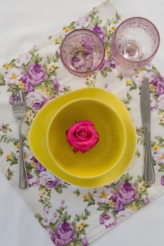 Overhead view of rose flower in a bowl with cutlery