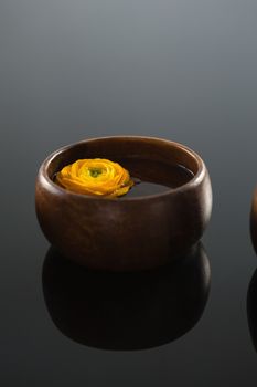Close-up of yellow rose in glass bowl with water on black background