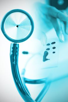 Part of the blue stethoscope against doctor holding microscope slide