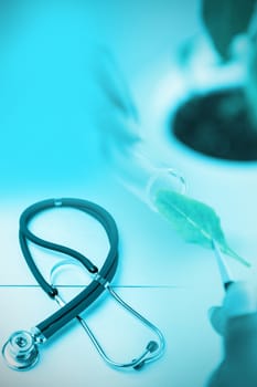 Stethoscope on desk against doctor experimenting with leaves