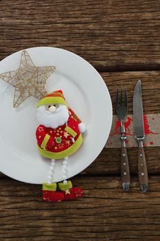 Santa claus with christmas ornament and cutlery on wooden table