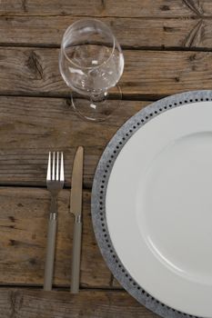 Overhead view of plate and wine glass with fork and butter knife on wooden table