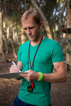 Close-up of trainer holding notepad in his hands in the forest on a sunny day