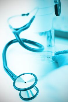 Blue stethoscope against doctor using microscope in laboratory