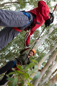 Man helping woman to cross zip line in the forest during daytime