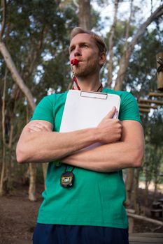 Athletic coach blowing whistle in the forest during daytime