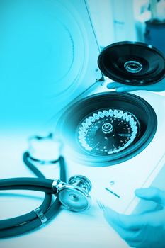 Stethoscope on desk against close up of a chemist using a centrifuge