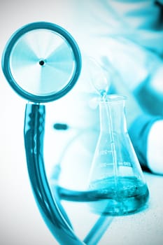 Part of the blue stethoscope against male chemist pouring a blue liquid