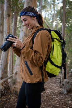 Young woman with backpack standing in the forest on a sunny day