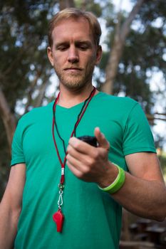 Close-up of trainer holding stop watch in his hand in the forest