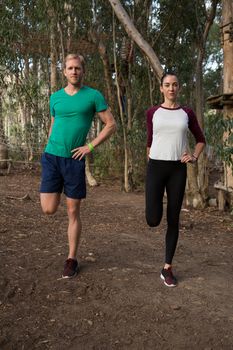 Woman exercising along with her trainer in the forest