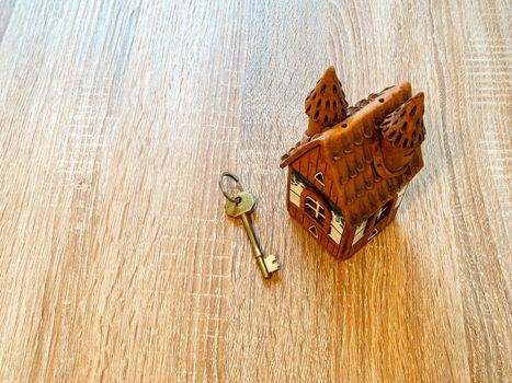 Model of a house and golden key On Wooden Table. Real estate agency, mortgage loan, lottery, buying property.Home loan and investment concept. Copy space