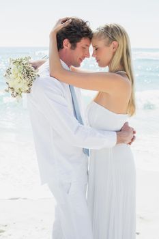 Romantic couple hugging each other on their wedding day at the beach