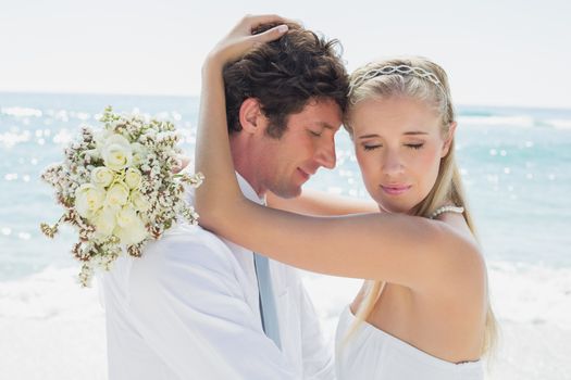 Romantic couple embracing on their wedding day at the beach
