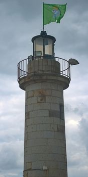 Stone lighthouse with green brittany flag at Cancale, France