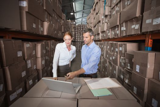 Warehouse team working together on laptop in a large warehouse