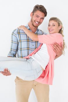 Portrait of young man carrying cheerful woman over white background