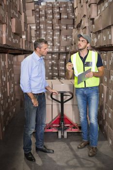 Warehouse manager talking with worker in a large warehouse