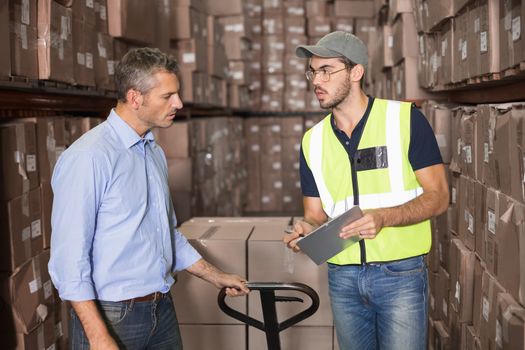 Warehouse manager talking with worker in a large warehouse