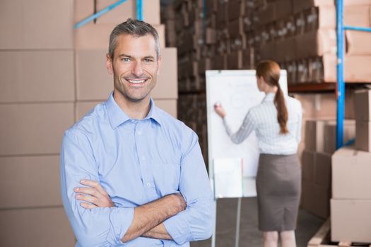 Warehouse manager smiling at camera in a large warehouse