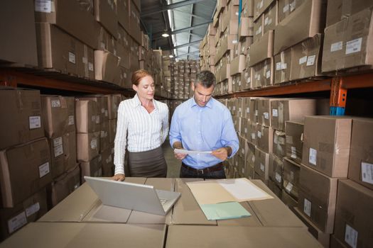 Warehouse team working together on laptop in a large warehouse