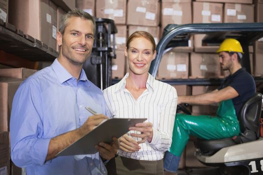 Warehouse team working together with clipboard in a large warehouse