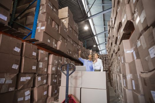 Warehouse team working together with trolley in a large warehouse