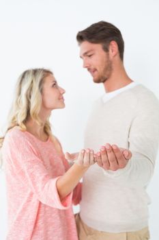 Attractive young couple holding out palms over white background