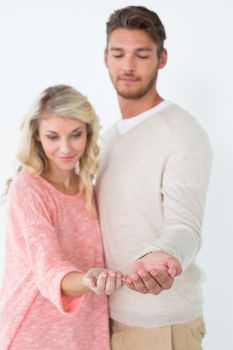 Portrait of attractive young couple showing palms over white background