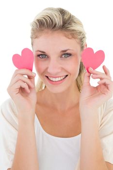 Portrait of smiling young woman holding pink hearts over white background