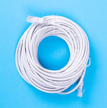 Ethernet cable rolled up, isolated, isolated on blue