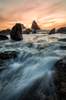 Sunset at a rocky beach with vivid warm colors and beautiful skies.