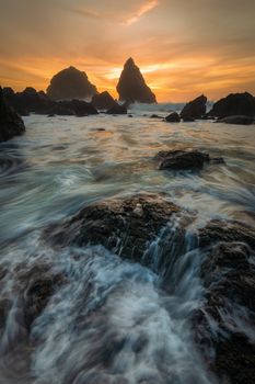 Sunset at a rocky beach with vivid warm colors and beautiful skies.