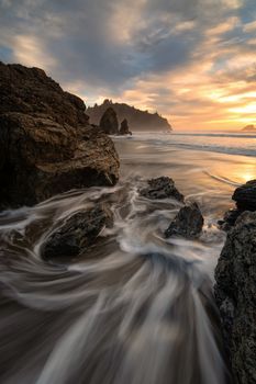 Sunset at a rocky beach with vivid warm colors and beautiful skies.