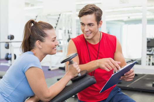 Personal trainer working with client holding dumbbell at the gym