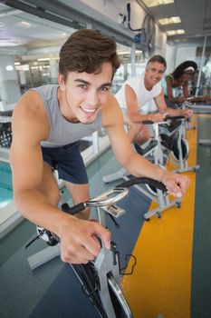Three fit people working out on exercise bikes at the gym