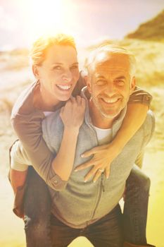 Laughing couple smiling at camera on the beach on a bright but cool day