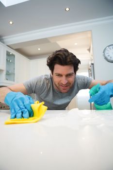 Young man cleaning kitchen worktop at home