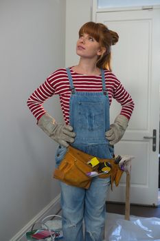 Female carpenter standing with hands on hip at home