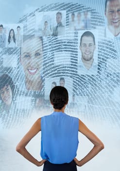 Digital composite of Woman standing hands on hips looking at interface of faces and a fingerprint